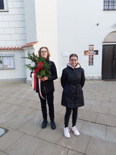 Młodzież stoi z kwiatami przed kościołem
