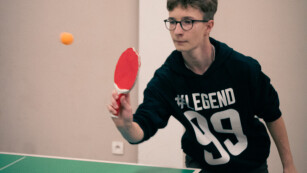 Chłopiec zagrywa piłeczkę do tenisa stołowego